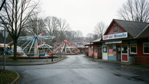 Vue réaliste d’un parc de loisirs familial fermé en hiver en Moselle, avec des manèges immobiles et une entrée déserte dans une ambiance sobre et économique.