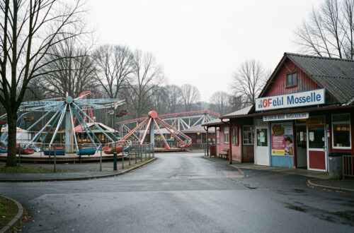 Vue réaliste d’un parc de loisirs familial fermé en hiver en Moselle, avec des manèges immobiles et une entrée déserte dans une ambiance sobre et économique.