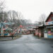 Vue réaliste d’un parc de loisirs familial fermé en hiver en Moselle, avec des manèges immobiles et une entrée déserte dans une ambiance sobre et économique.